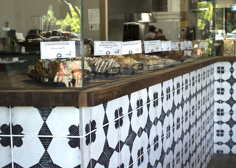 The pastry display case featuring abstract black and white tile work and butcher-block countertops